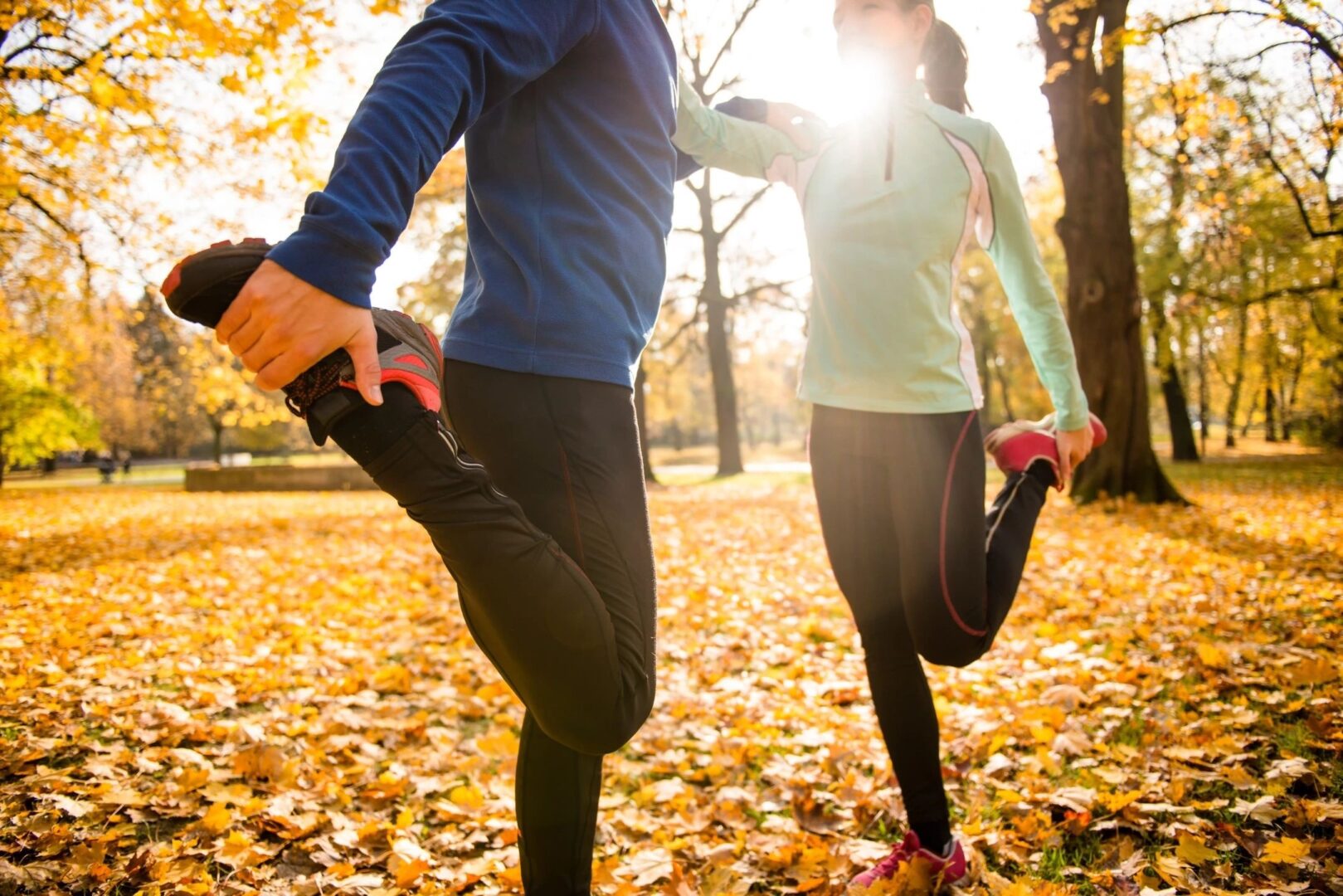 A man and woman stretching in the leaves.